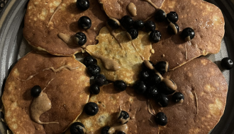 plate of coconut flour pancakes with almond butter and blueberries