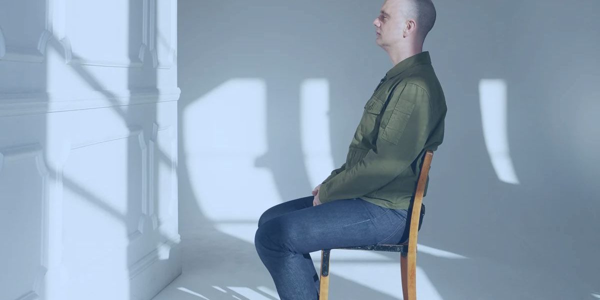 A person seated in a chair doing nothing but looking ahead.