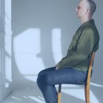 A person seated in a chair doing nothing but looking ahead.