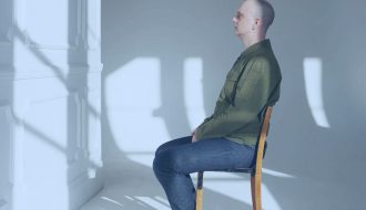 A person seated in a chair doing nothing but looking ahead.