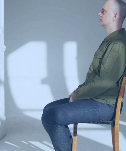 A person seated in a chair doing nothing but looking ahead.