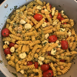 A pot of pasta, beans, tomatoes, mozzerella, basil, and a vinaigrette dressing