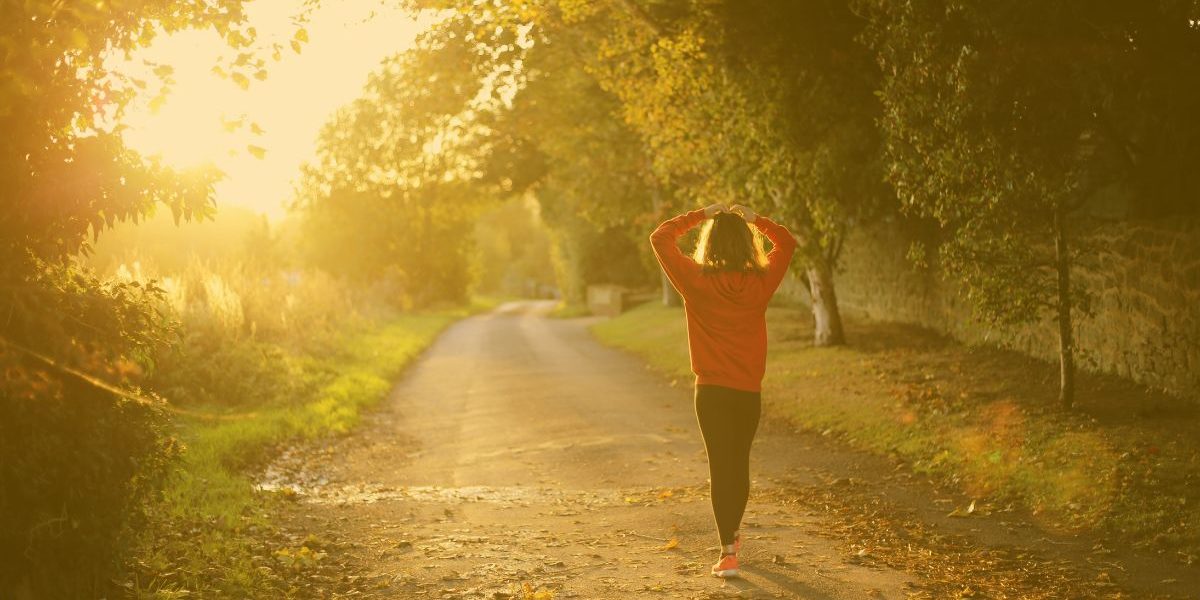 person walking on a road in the sun